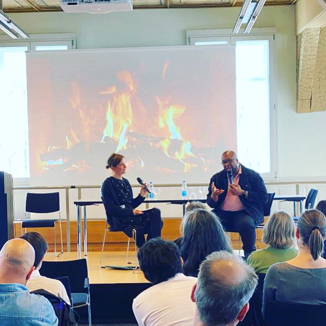 Christopher Lafayette taking part in a fireside conversation in front of a seated university audience.