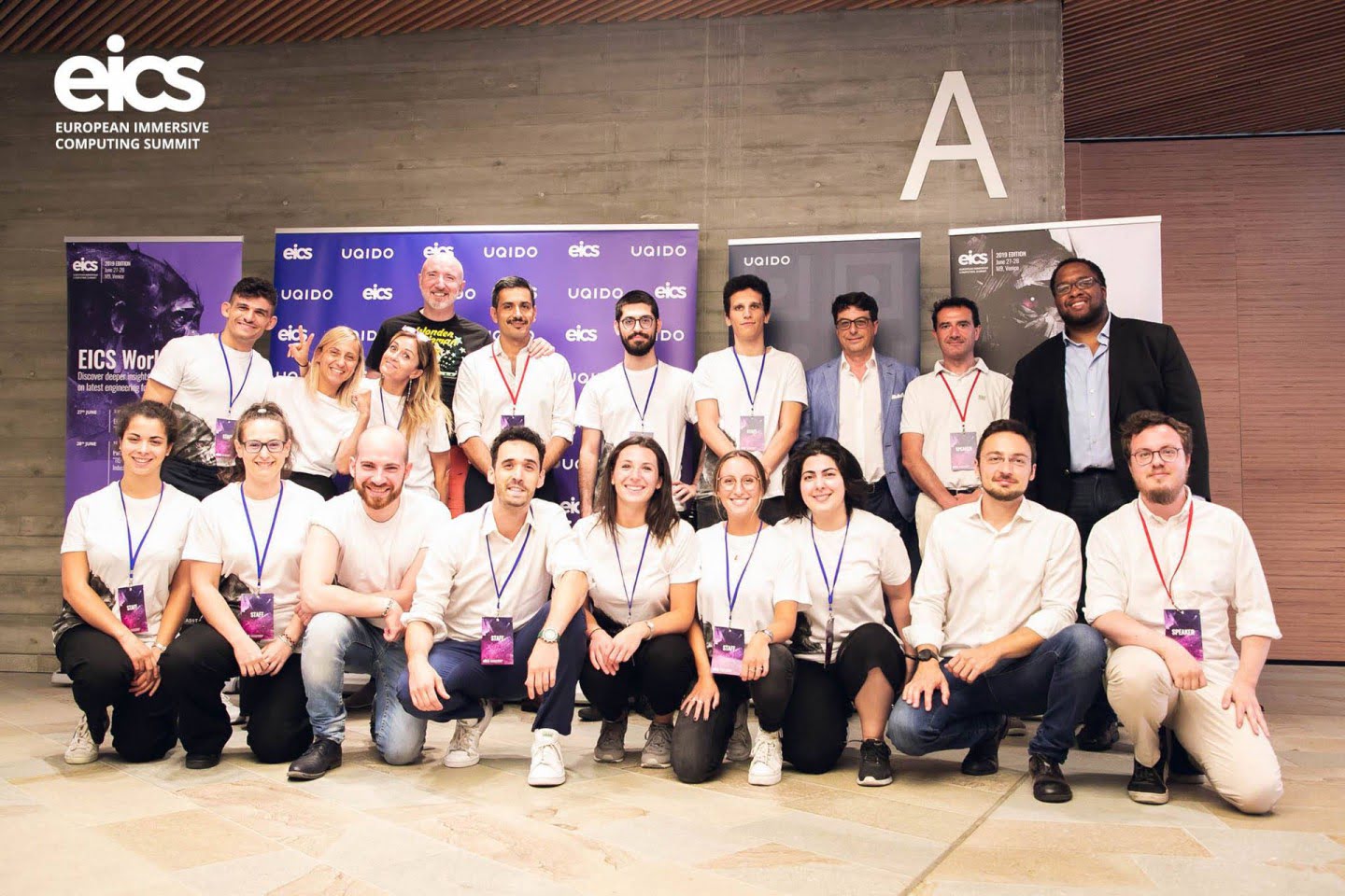 A large group poses in front of the European Immersive Computing Summit backdrop.