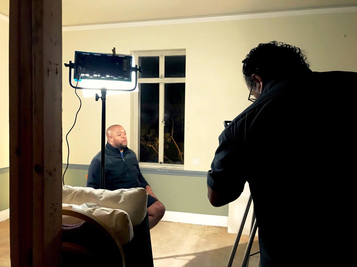 A camera operator records a seated interview with Christopher Lafayette.