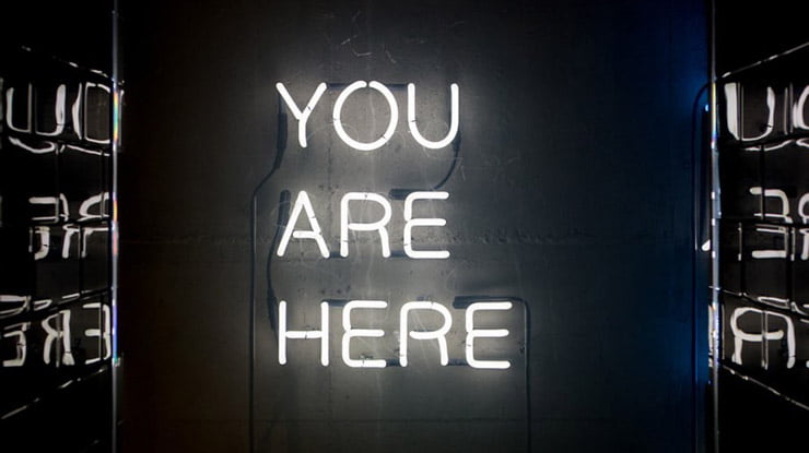 A neon sign displaying “You Are Here.”
