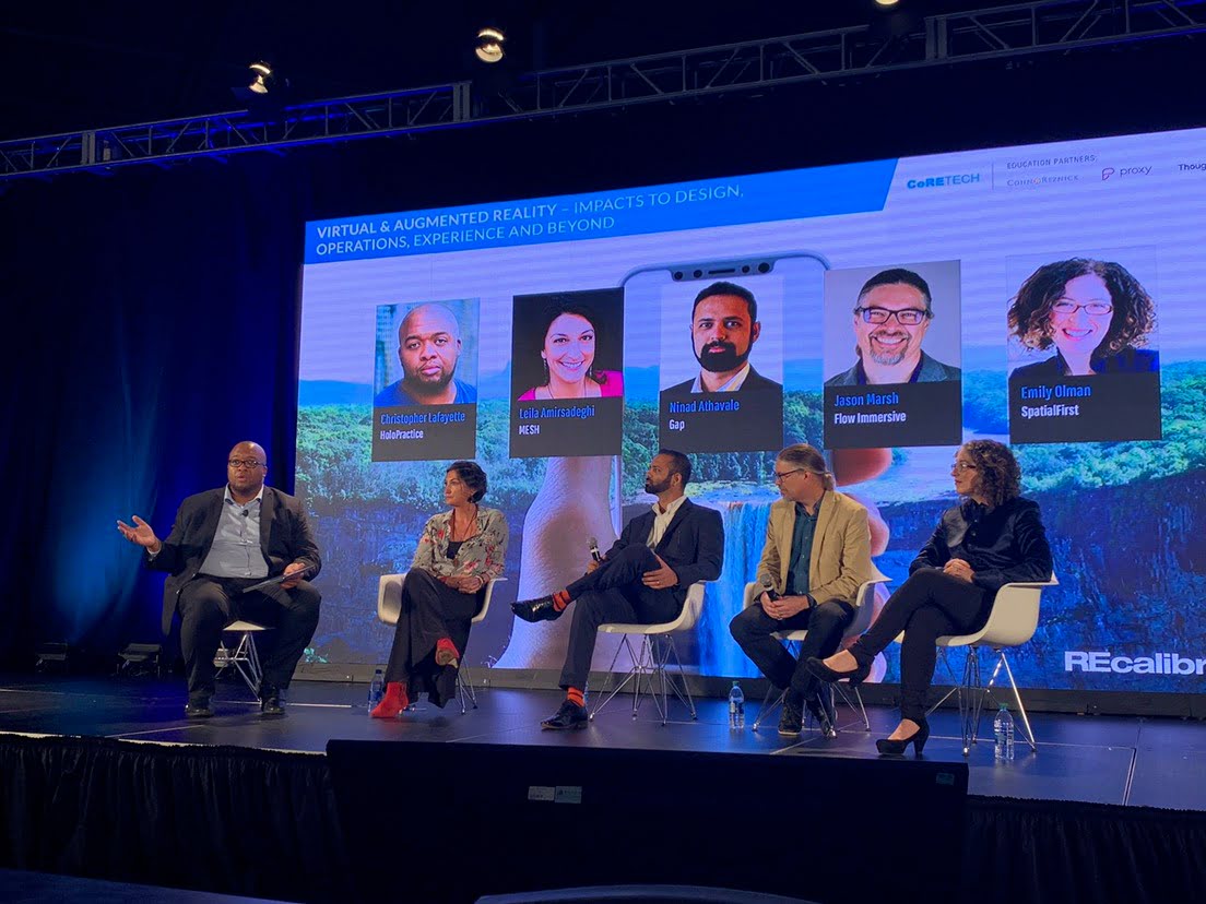 Christopher Lafayette gestures while seated with four panelists beneath a screen titled Virtual & Augmented Reality — Impacts to Design, Operations, Experience and Beyond.